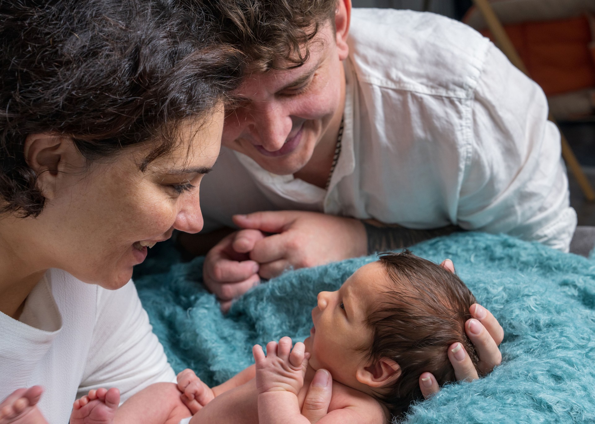 Happy family with a newborn baby. Mom and dad looking tenderly at the baby.
